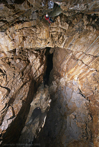 People climbing in a deep cave