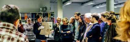 A group of people listening to a Society representative talk about an artefact from the collections.