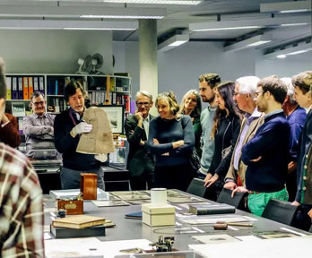 A group of people listening to a Society representative talk about an artefact from the collections.
