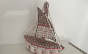 A decorative boat made from shells, with larger shells making the bow of the boat and smaller shells to decorate the sail