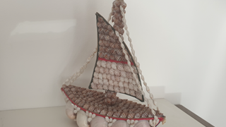 A decorative boat made from shells, with larger shells making the bow of the boat and smaller shells to decorate the sail