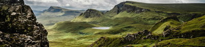 Green grass on a mountainouse landscape under a cloudy grey sky.