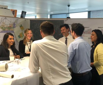 Six professionals standing around a table having a discussion