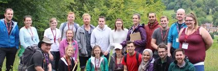 A group of trainee teachers gathered together in the outdoors during a fieldwork day, all smiling and holding geography fieldwork equipment