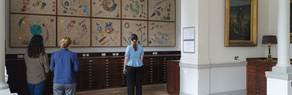 A group of people pictured from the back, viewing Hormazd Narwiella's mural in the Map Room of the Royal Geographical Society.