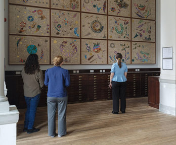 A group of people pictured from the back, viewing Hormazd Narwiella's mural in the Map Room of the Royal Geographical Society.