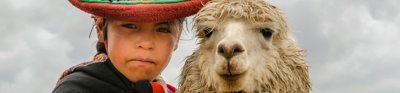 A woman with a sombrero standing with a llama
