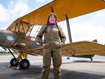 Amanda standing in pilot suit in front of a biplane.