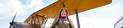 Amanda standing in pilot suit in front of a biplane.