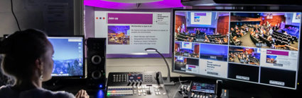 A person sat at a desk working in the recording booth of a lecture theatre.