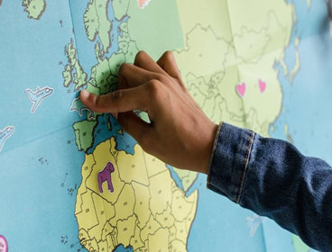 A child pointing to the UK on a map of the world.