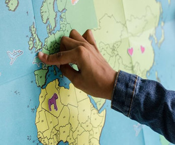 A child pointing to the UK on a map of the world.