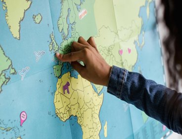 A child is pointing to the UK on a map of the world
