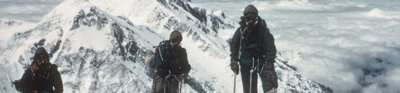 Three climbers ascenting snow-capped mountain.