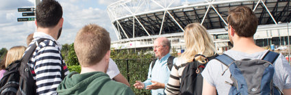 A group of teachers standing outside the London 2012 Olympic stadium in Stratford, London. They are being guided by a fieldwork expert in how to lead fieldwork for schools in the area.