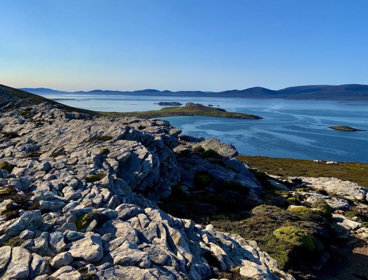 Rocky landscape with sea in the background against a clear blue sky.