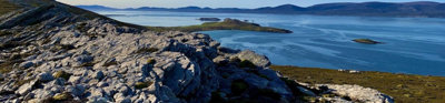 Rocky landscape with sea in the background against a clear blue sky.