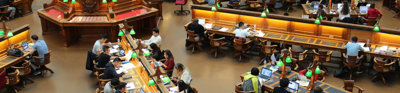 Rows of students working at long desks in a library as seen from above.