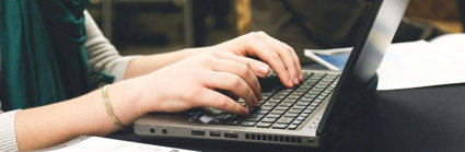 Close up of a person's hands typing on a laptop.