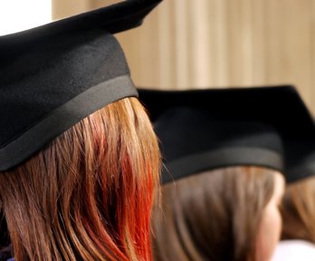 Back of heads of three people wearing univiersity graduation caps. 