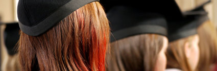 Back of heads of three people wearing square university graduation caps. 