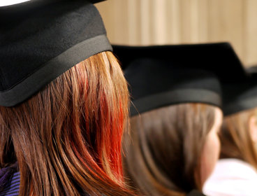 Back of heads of three people wearing square university graduation caps. 