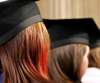 Back of heads of three people wearing square university graduation caps. 