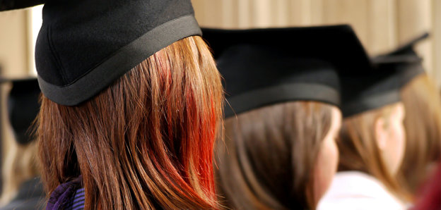 Back of heads of three people wearing square university graduation caps.