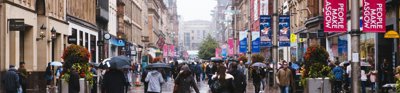 Poeple walk with either umbrellas or hoods up as it rains on Buchanan Street, Glasgow, United Kingdom