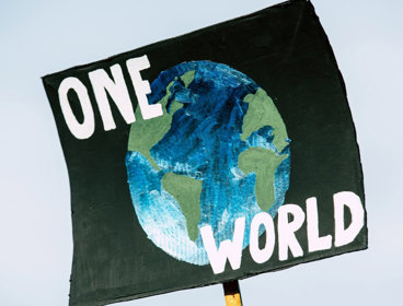 Cardboard sign that reads 'one world' with image of the earth.