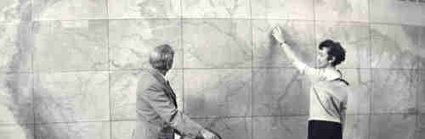Historic photograph of man and woman standing in front of large map and with globe