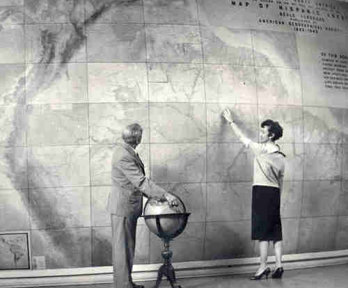 Historic photograph of man and woman standing in front of large map and with globe