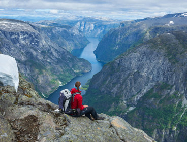 Person looking out across a mountain valley. A river meanders through the valley.