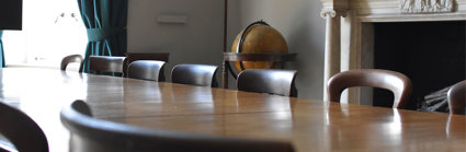 Close up of a large table and chairs in an old and stately meeting room. 