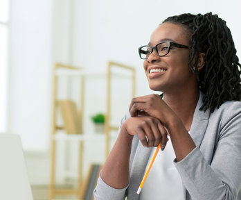 Smiling young professional sitting at a desk in a brightly lit room.