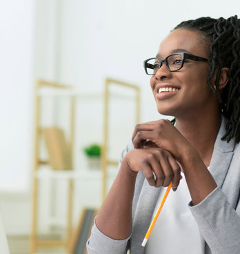 Smiling young professional sitting at a desk in a brightly lit room.