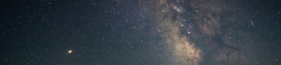 Person standing beside tent with a starry sky behind