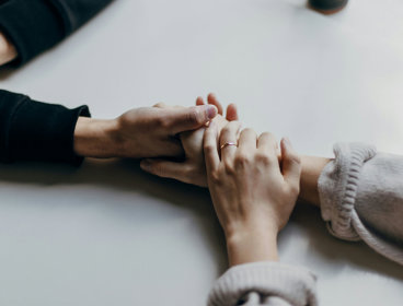 Close up of two pair of hands holding each other in a reassuring manner.