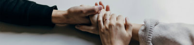 Close up of two pair of hands holding each other in a reassuring manner.