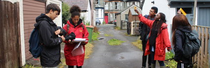 Group of young people taking measurements in a lane behind a row of houses.