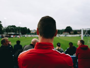 A man pictured from the back watching a football match