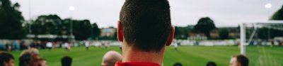 A man pictured from the back watching a football match