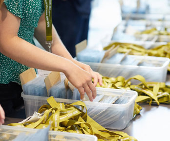 A person sorting green lanyards and badges into plastic boxes.