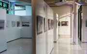 A photographic exhibition displayed on white panels in a modern pavilion.