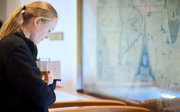 A person holding a drink looking into a display cabinet.