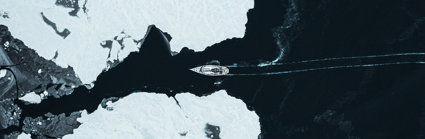 A ship crossing through two glaciers seen from far above.