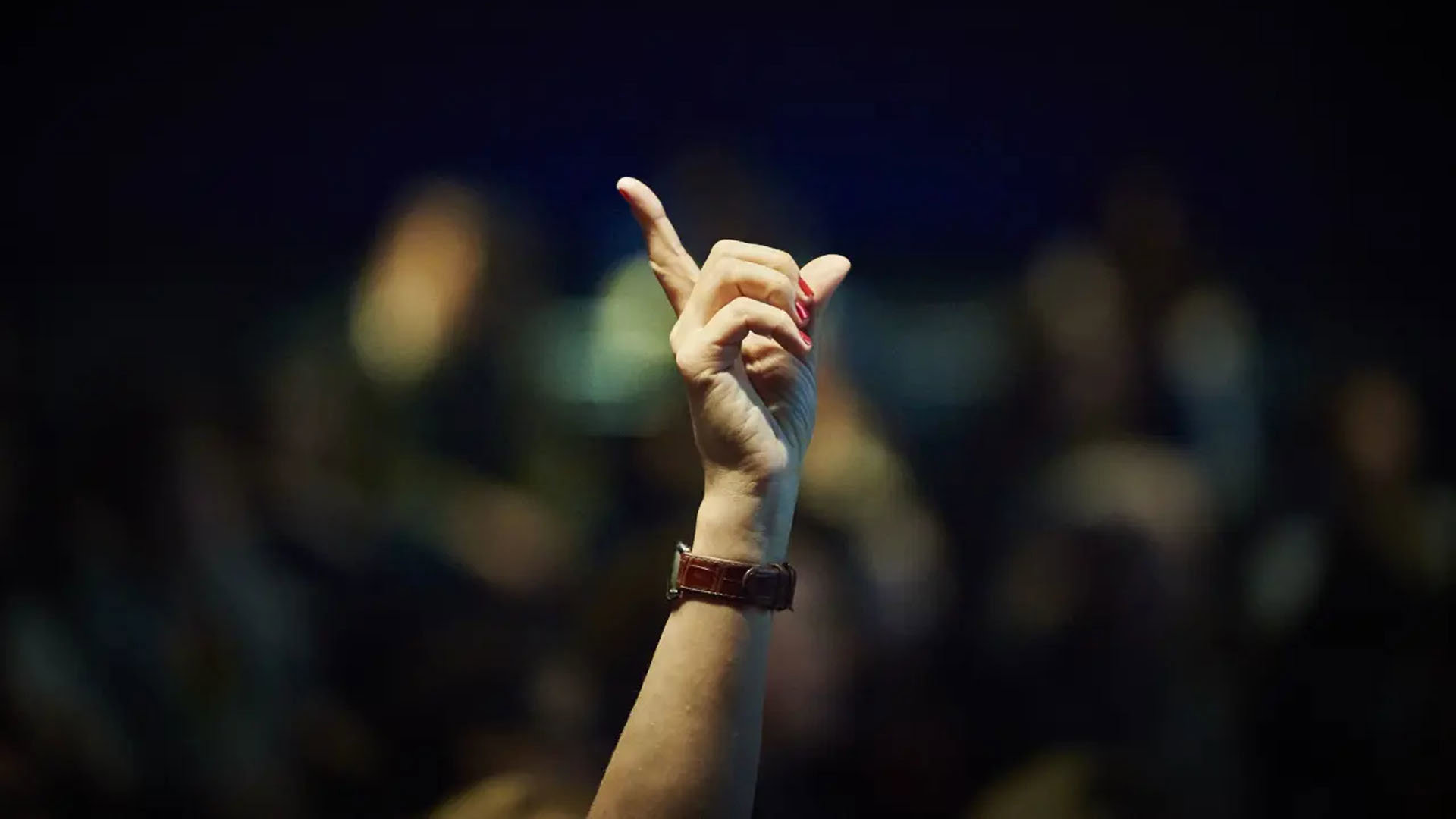 A hand is raised in a lecture theatre to display the desire to ask a question.