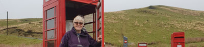 Heather standing in red telephone box in rural landscape