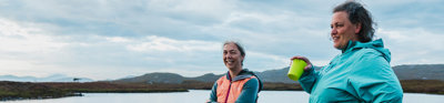 Two people standing with a canoe by water