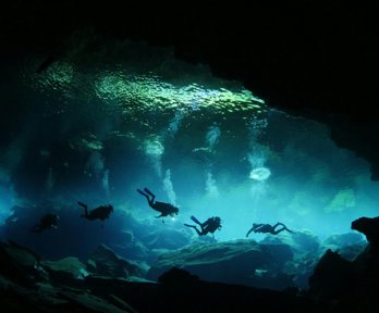A group of four divers in an underwater cave.